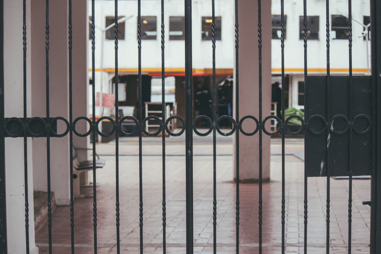 A modern iron gate showcasing minimalist architecture with an urban backdrop.